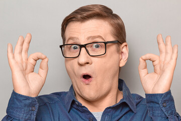 Portrait of amazed impressed blond mature man showing okay gestures