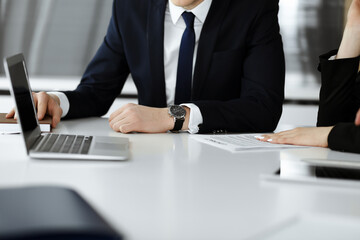 Unknown businessmen and woman sitting, working and discussing questions at meeting in modern office, close-up