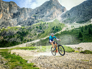 Fototapeta premium Man doing mountain biking in a mountain route - Sport Man riding a mountain bike passes in through a shallow stream running through tranquil nature