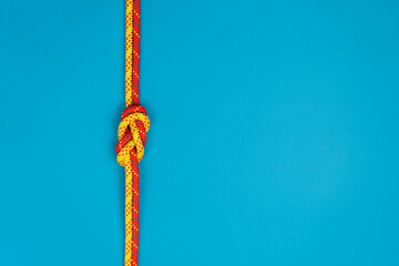 Figure-eight knot with red and yellow climbing ropes on blue background