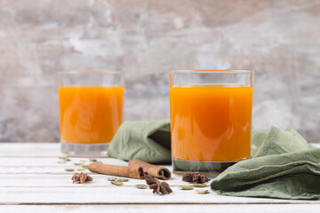 Two glasses of pumpkin juice.Spices cinnamon sticks and star anise. Gray blurred background