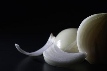 Fresh onion bulbs on black background. Bulb onion is rich in vitamins, useful spring. Onion peel on a dark background. Raw sliced onions.