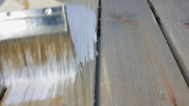 a brush paints gray boards with white paint. Painting with white paint