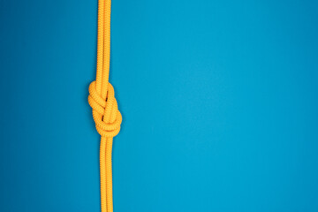 Figure-eight knot with yellow climbing rope on blue background