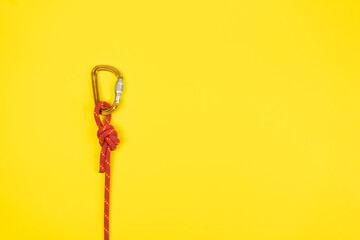 Overhand knot with orange carabiner and red climbing rope on yellow background