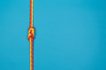 Figure-eight knot with red and yellow climbing ropes on blue background