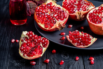 Large pomegranate, broken into pieces. On a dark background. Grains are scattered nearby. Autumn concept. Vitamins, healthy lifestyle.