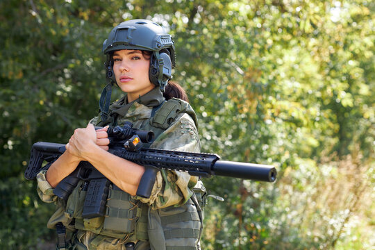 attractive brave military woman with a gun in forest, survival in wild forest, caucasian female in green suit camouflage suit with rifle or weapon