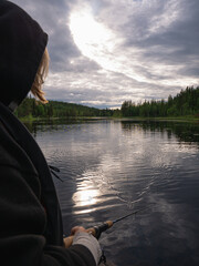Boy fishes with a throwing rod in hopes  of catching a pike or bass in the wilderness of northern Sweden on a beautiful summer day