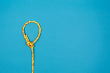 Bowline loop knot with yellow climbing rope on blue background