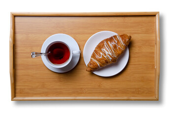Cup of black tea and croissant on wooden tray on white background isolation, top view