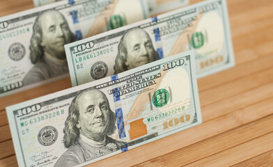 100 Dollars bill and portrait Benjamin Franklin on USA money banknote. Hundred dollar bills on wooden background..