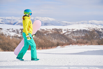 Woman with snowboard against background of mountains