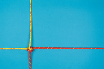 Double knot with red and yellow climbing ropes on blue background