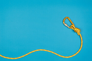 Overhand knot with yellow carabiner and climbing rope on blue background