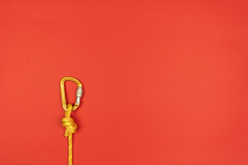 Overhand knot with orange carabiner and yellow climbing rope on red background
