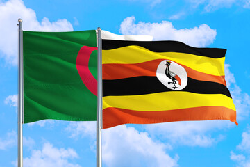 Uganda and Algeria national flag waving in the windy deep blue sky. Diplomacy and international relations concept.