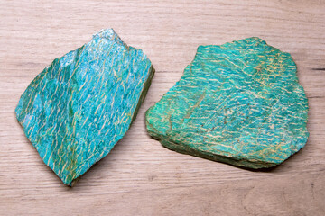 Two pieces of beautiful bright semiprecious mineral amazonite lying on a wooden surface