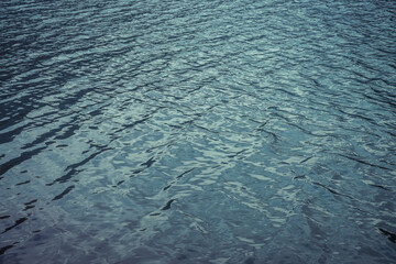 Texture of purple calm water of mountain lake. Meditative ripples on water surface. Nature minimal background of violet lake. Natural backdrop of clear dark blue water. Full frame of lake fragment.
