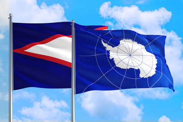 Antarctica and American Samoa national flag waving in the windy deep blue sky. Diplomacy and...