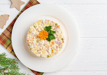 Olivier salad. Traditional russian dish for celebrating new year and christmas. White wooden table background. Festive table setting. Fir tree branches, wooden fir tree and star. Top view. Flat layout