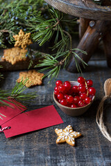 Cup with red currant berries with Christmas decorations, greeting cards and gingerbread