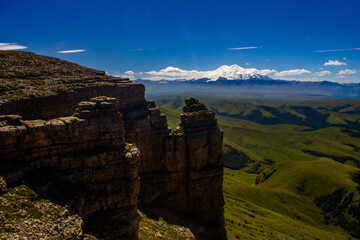 An excellent view from the plateau to the extinct volcano and the snowy peak of Mount Elbrus. Below is a green gorge