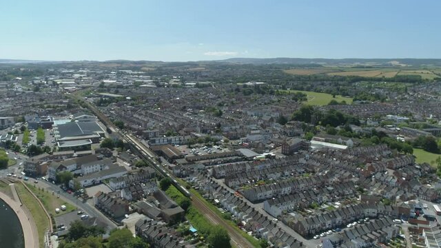 A train makes its way through the city of Exeter. Residential district in the foreground, and an industrial estate in the background