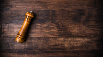 wooden pepper pot on a brown wooden table with free space for text