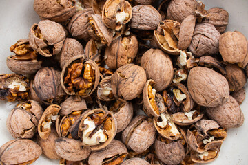 Group of cracked walnuts on white background. Close up of walnuts. Autumn harvest. Dried nuts. Rural nature background. Raw healthy food. Nuts shell. Tasty organic snack. Vegetarian food.