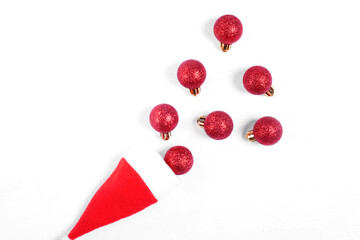 Red baubles rolling out of the santa hat against the white background. Flapper imitation. Christmas...