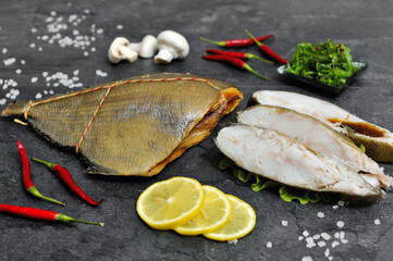 Appetizing, delicious smoked fish on the kitchen board. Smoked fish with spices and vegetables.