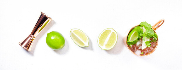 Moscow mule cocktail in copper mug with lime, ginger beer, vodka and mint. White table, copy space