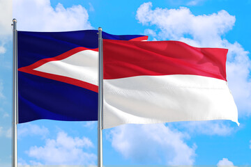 Indonesia and American Samoa national flag waving in the windy deep blue sky. Diplomacy and international relations concept.
