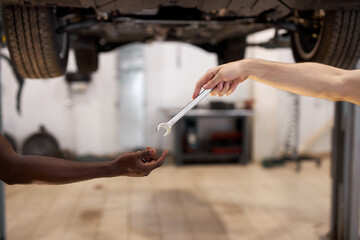 two auto mechanic colleagues giving tools to each other, cropped hands, close-up photo of tools and hands. transport, car concept