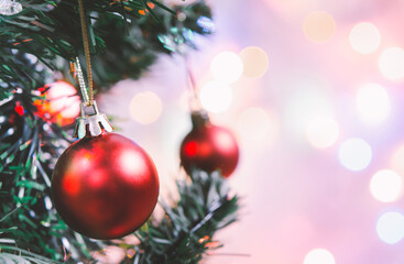 Fototapeta premium Christmas decoration. Red balls hanging on pine branches christmas tree garland and ornaments over abstract bokeh background with copy space