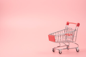 Shopping concept - Red shopping cart on pink background with copy space.