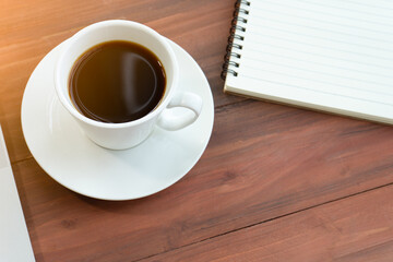 Coffee served in a cup, placed beside a notebook