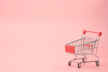 Shopping concept - Red shopping cart on pink background with copy space.