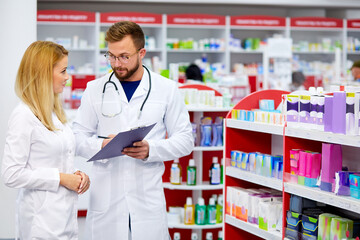 team of young caucasian chemists or druggists discussing medicines, check medical indications, in...