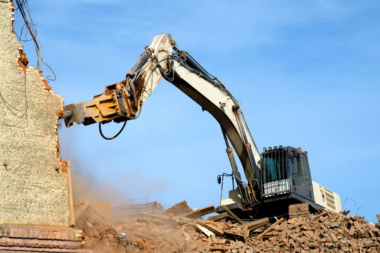 excavator demolishing a brick building. Machinery Demolishing Building