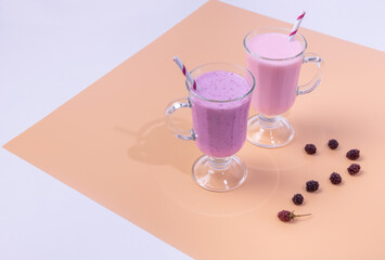 two glasses of BlackBerry and raspberry smoothies on a colored background. The concept of healthy eating