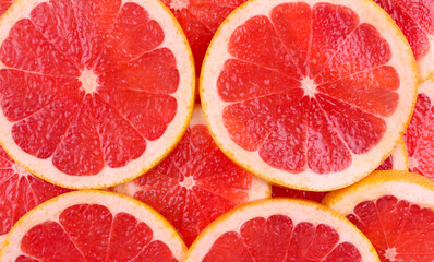 Fototapeta na wymiar Background of sliced red round grapefruit