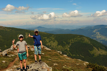Two small children, brothers boys standing on one rocky peak, a mountain of Carpathian mountains, happy children, children on a hike.