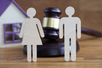 Wooden figures of man and woman standing on table near judges hammer and toy house closeup. Divorce mediation concept - obrazy, fototapety, plakaty