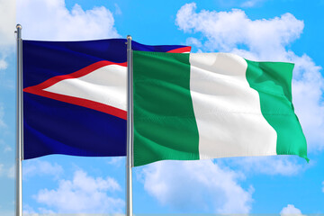 Nigeria and American Samoa national flag waving in the windy deep blue sky. Diplomacy and international relations concept.