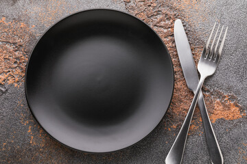 Empty black plate and cutlery on the table, top view. Food background