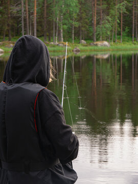 Pojke fiskar med fiskesp&ouml; i hopp om att f&aring;nga en g&auml;dda eller abborre i en sj&ouml; i norra svenska vildmarken en fin sommarkv&auml;ll.