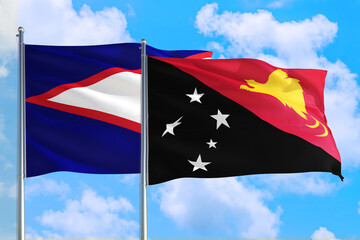 Papua New Guinea and American Samoa national flag waving in the windy deep blue sky. Diplomacy and international relations concept.