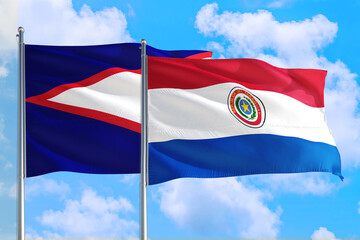Paraguay and American Samoa national flag waving in the windy deep blue sky. Diplomacy and international relations concept.